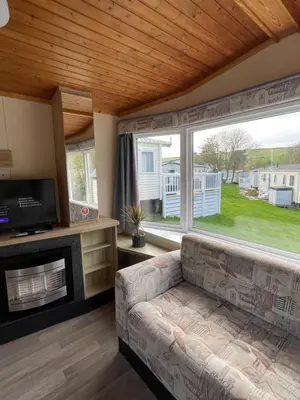 a living room with a couch and a large window at Newquay Bay Holiday Resort Caravan 73 in Porth