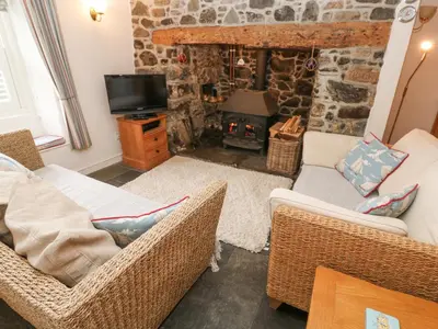 a living room with two chairs and a stone fireplace at Penhaven in Helston