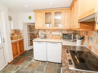 a kitchen with white appliances and wooden cabinets at Penhaven in Helston