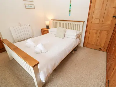a bedroom with a bed with white sheets and a wooden door at Penhaven in Helston
