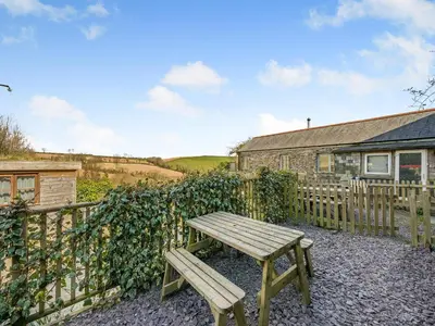 a wooden picnic table in front of a fence at Horseshoe Cottage - Uk48252 in Downderry
