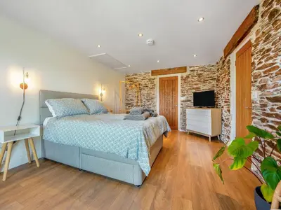 a bedroom with a bed and a stone wall at Horseshoe Cottage - Uk48252 in Downderry