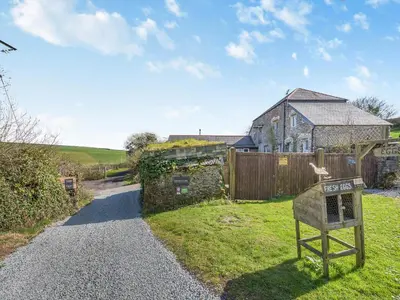 a stone house with a sign in the yard at Roosters Rest - Uk48255 in Downderry