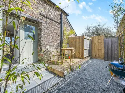a garden with a brick building and a wooden fence at Roosters Rest - Uk48255 in Downderry