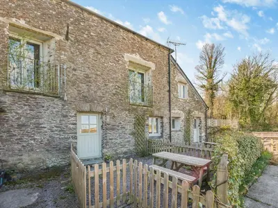 a brick building with a wooden fence and a wooden bench at Roosters Rest - Uk48255 in Downderry