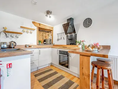 a kitchen with white cabinets and a wooden counter top at Roosters Rest - Uk48255 in Downderry