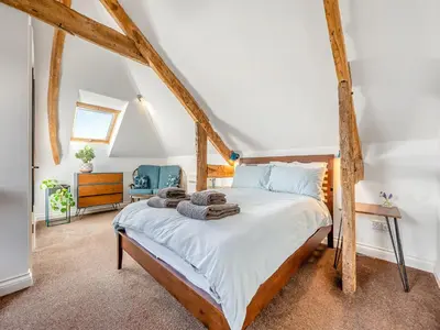 a bedroom with a bed with white sheets and wooden beams at Roosters Rest - Uk48255 in Downderry