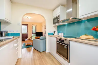 a kitchen with blue and white cabinets and a living room at 2 Bed in Padstow oc-t30052 in Padstow