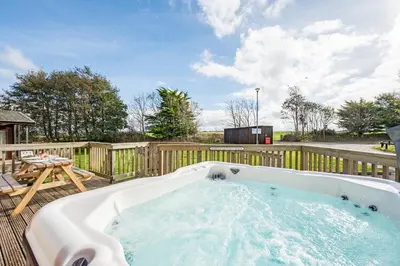 a hot tub on a deck with a wooden fence at 3 Bed in St. Merryn oc-r30137 in St Merryn
