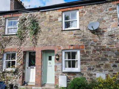 a brick house with a green door and windows at 15 The Moors in Lostwithiel