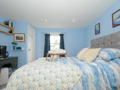 a blue bedroom with a bed with a chair on it at 15 The Moors in Lostwithiel