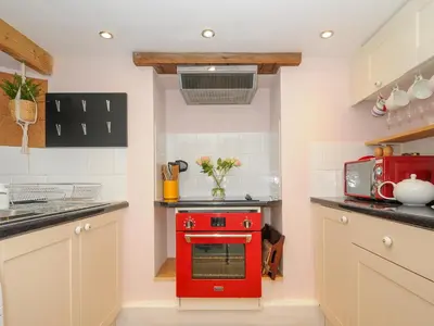 a red stove in a kitchen with white cabinets at 15 The Moors in Lostwithiel