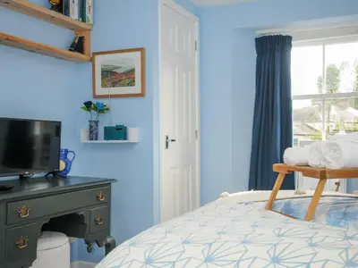 a bedroom with blue walls and a bed with a television at 15 The Moors in Lostwithiel