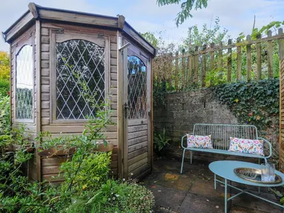 a wooden shed with a bench and a table in a garden at 15 The Moors in Lostwithiel