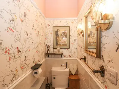 a bathroom with a toilet and flowers on the wall at Harvey's House in Helston