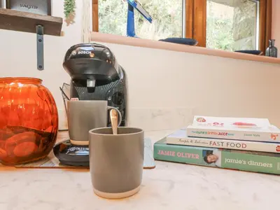 a counter with a coffee maker and books on it at Harvey's House in Helston