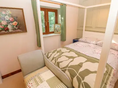 a bedroom with a bed and a chair at Harvey's House in Helston