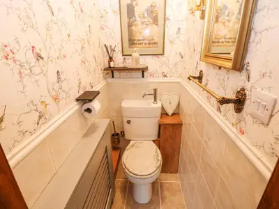 a bathroom with a toilet and a tub with wallpaper at Harvey's House in Helston