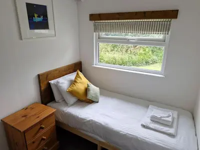 a small bedroom with a bed with a window at Trenant Cottage in Fowey