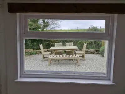 a view of a table and bench through a window at Trenant Cottage in Fowey