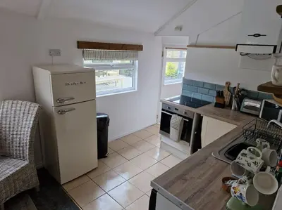 a kitchen with a refrigerator and a sink in it at Trenant Cottage in Fowey