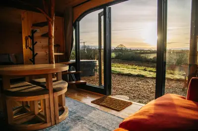 a living room with a large window and a couch at The Palm at OLJU Lodges in Ponsanooth