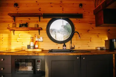 a kitchen with a sink and a round window at The Palm at OLJU Lodges in Ponsanooth