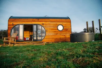 a tiny house sitting on top of a grass field at The Palm at OLJU Lodges in Ponsanooth