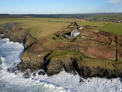 an aerial view of a house on a cliff next to the ocean at Wildly Romantic Cliff Top Apartment in Porthleven