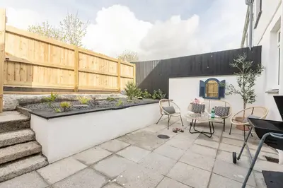 a patio with chairs and a table and a fence at Stylish apartment with parking - Flat 2 Mill House in Penryn