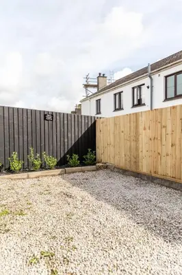 a house with a wooden fence and a gravel driveway at Stylish apartment with parking - Flat 2 Mill House in Penryn