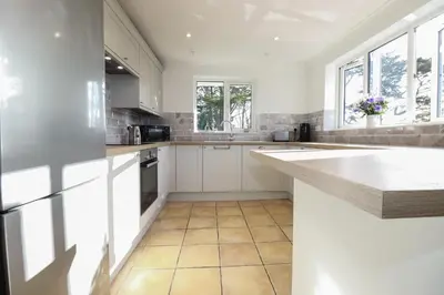 a kitchen with white cabinets and a tile floor at Surf Break in Wadebridge