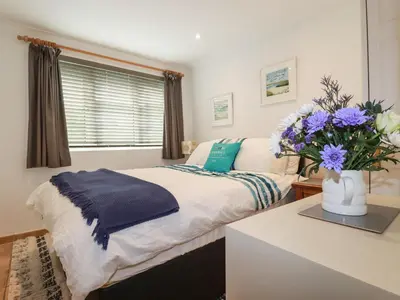 a bedroom with a bed and a vase of flowers at Surf Break in Wadebridge