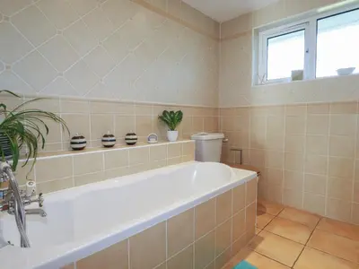 a bathroom with a tub and a window and a plant at Surf Break in Wadebridge