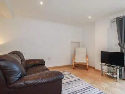 a living room with a leather couch and a television at Surf Break in Wadebridge