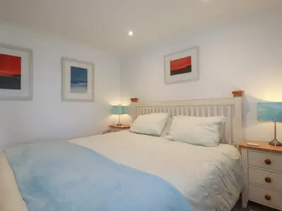 a bedroom with a bed with a blue blanket on it at Surf Break in Wadebridge