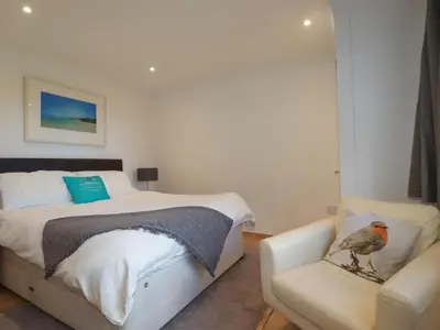 a bedroom with a bed and a bird sitting on a chair at Surf Break in Wadebridge