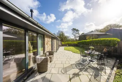 a patio with a table and chairs and an umbrella at Whitewood in Camborne