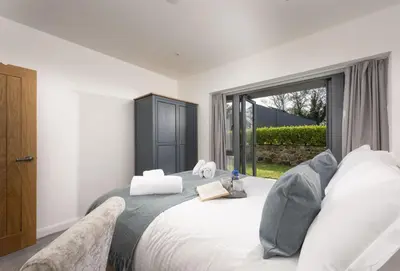 a bedroom with a large bed with a large window at Whitewood in Camborne