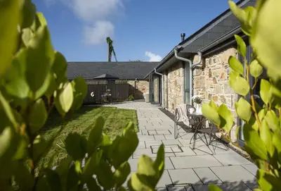 a garden with chairs and a stone building at Whitewood in Camborne