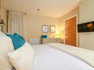 a bedroom with a white bed with blue pillows at Kerensa in St Austell