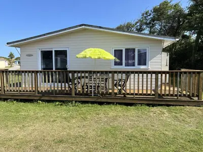 a house with a deck with a yellow umbrella at Chalet 3 Wipeout in Hayle