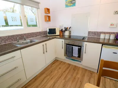 a kitchen with white cabinets and a sink at Chalet 3 Wipeout in Hayle