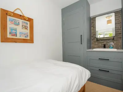 a bedroom with a white bed and a sink at Slipway 14 in Wadebridge