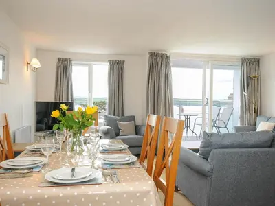 a living room with a dining room table with flowers on it at Slipway 14 in Wadebridge