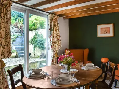 a dining room with a table and a large window at Gew Cottage in Helston