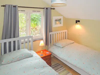two twin beds in a bedroom with a window at Gew Cottage in Helston