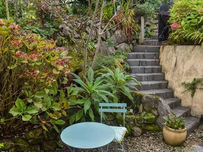a blue table and a blue chair in a garden at Gew Cottage in Helston