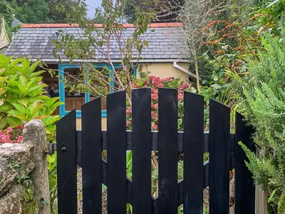 a black fence in front of a house at Gew Cottage in Helston