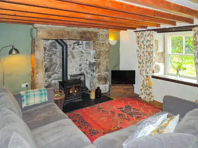 a living room with a couch and a fireplace at Gew Cottage in Helston